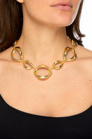Golden Bouche necklace by Silvia Gnecchi featuring a delicate chain and elegant pendant against a neutral background.