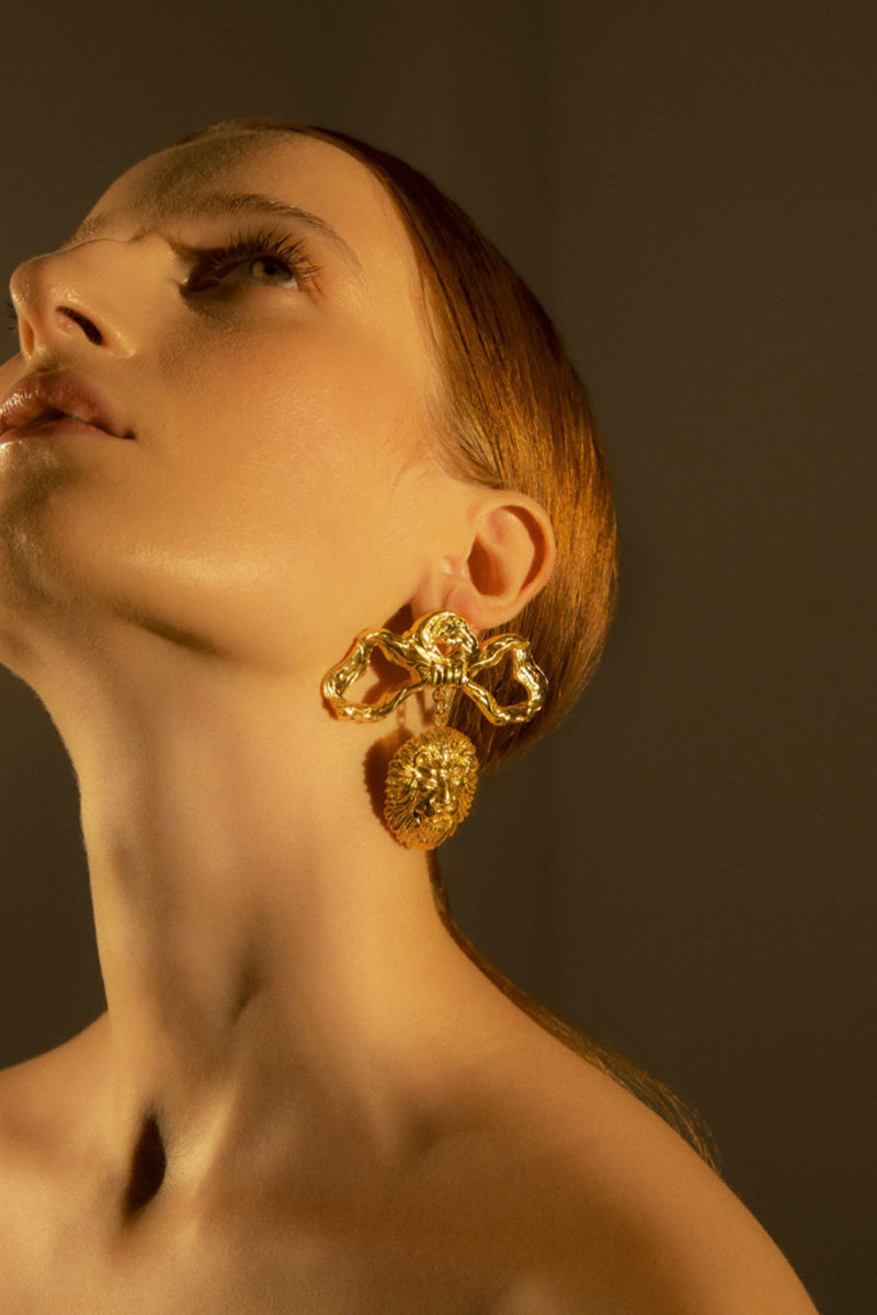Natia x Lako lion bow earrings featuring gold-tone earrings with a lion motif and bow design, stylish and bold accessory.