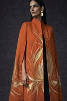 Nadya Shah Solaris Cape in Solar Amber, stylish jacket with warm, vibrant orange fabric, shown on a hanger.
