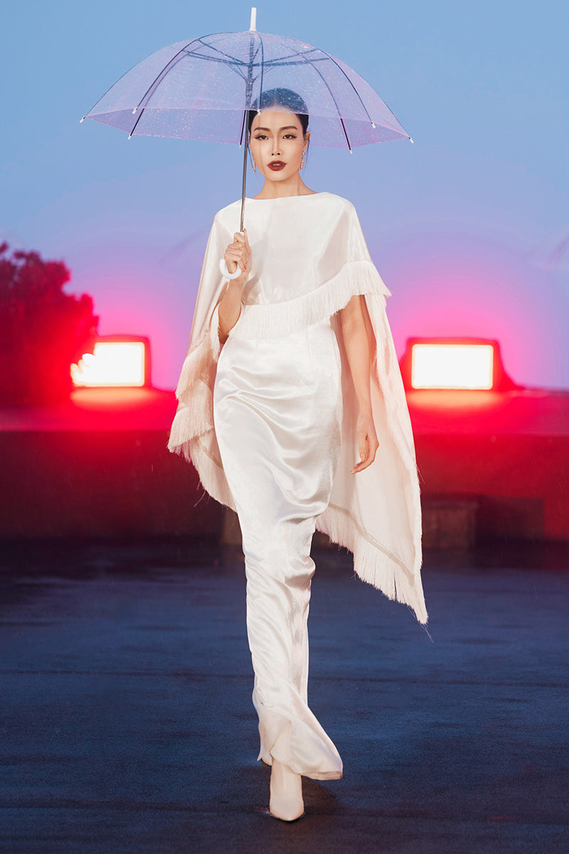 Cream Valenciani column gown with fringed trim cape, elegant long dress featuring intricate detailing and flowing silhouette.