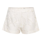SÉLONE JORA white fringe shorts with a high-waist fit and layered fringe detail, styled for casual summer wear.