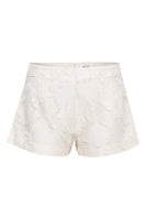 SÉLONE JORA white fringe shorts with a high-waist fit and layered fringe detail, styled for casual summer wear.