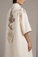 Nadya Shah Belle Epoque ivory coat, tailored with elegant lapels and long sleeves, displayed on a hanger against a neutral background.