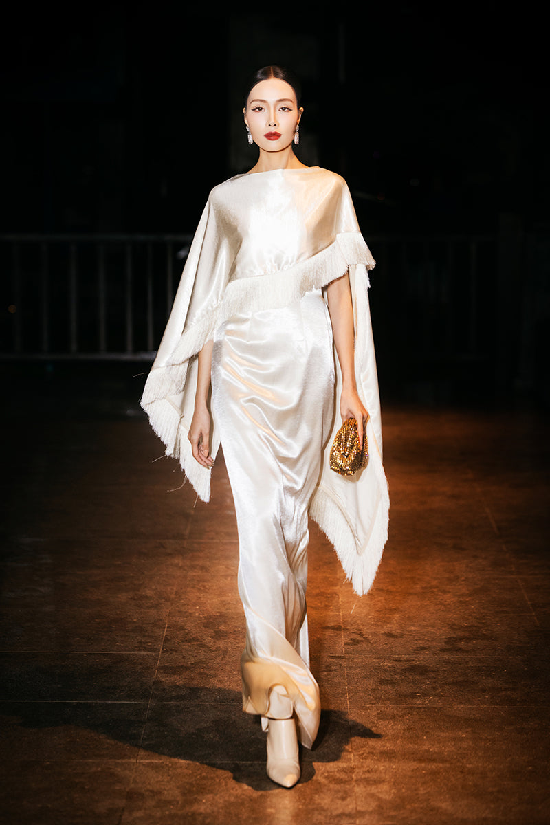 Cream Valenciani column gown with fringed trim cape, elegant evening dress featuring flowing fabric and stylish cape detail.