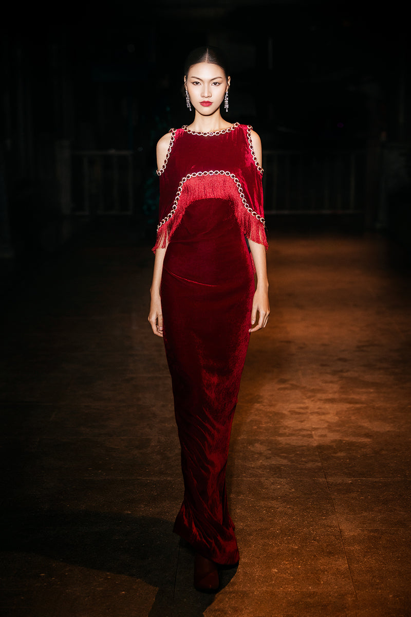 Red Valenciani shoulder cutouts cape gown with flowing fabric and elegant design, showcased on a model.