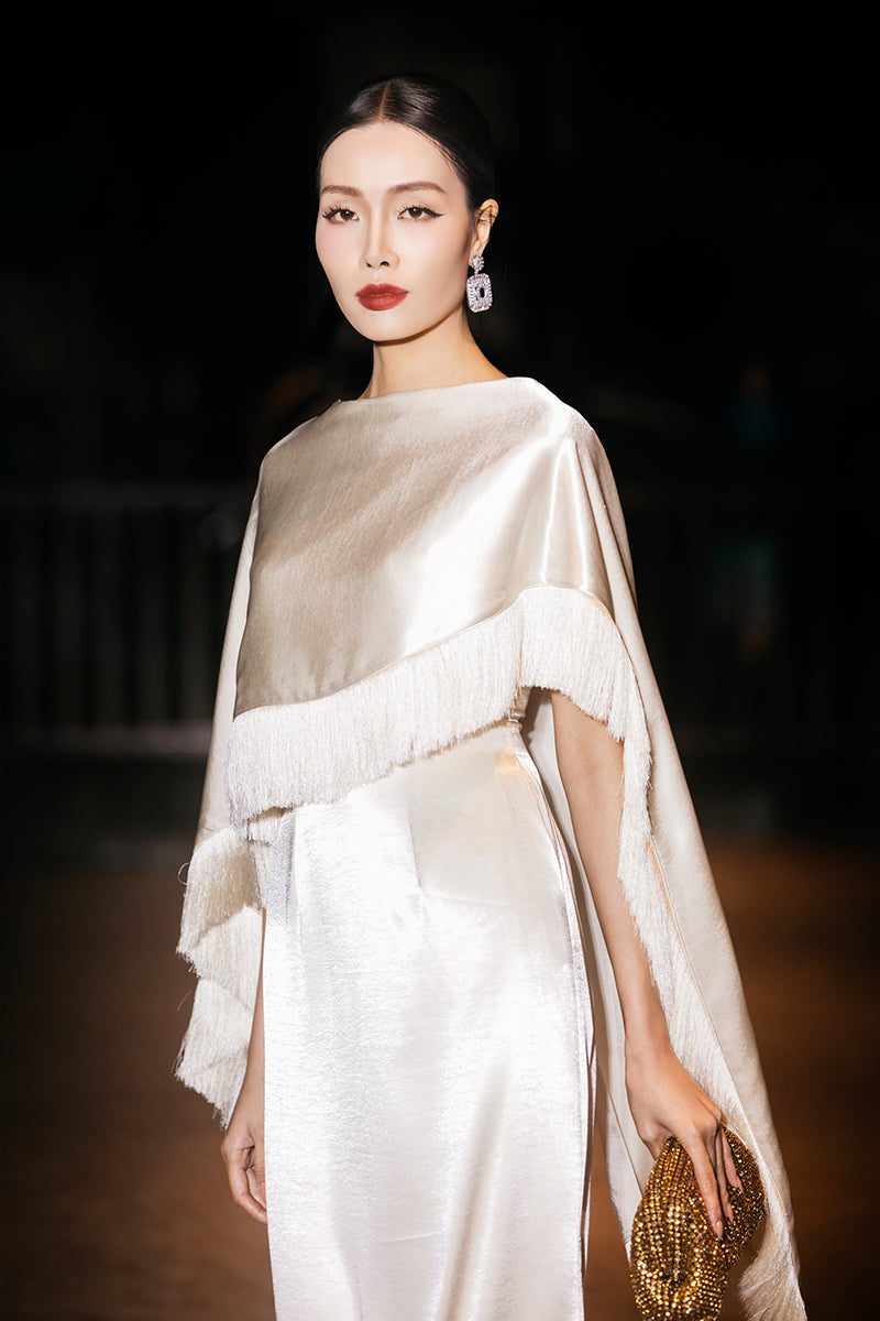 Cream Valenciani column gown with fringed trim cape, elegant and flowing, perfect for formal occasions.