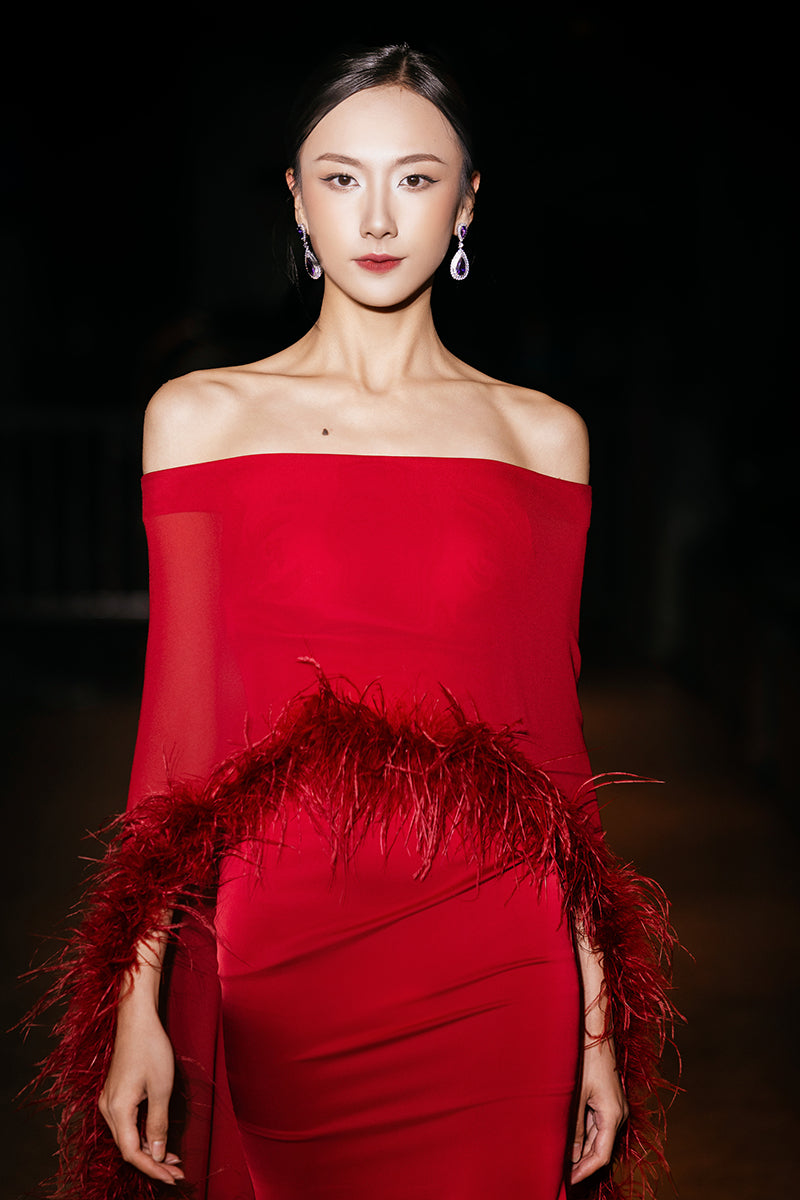 Red Valenciani gown with ostrich feather trim cape, elegant formal dress featuring flowing fabric and luxurious feather accents.