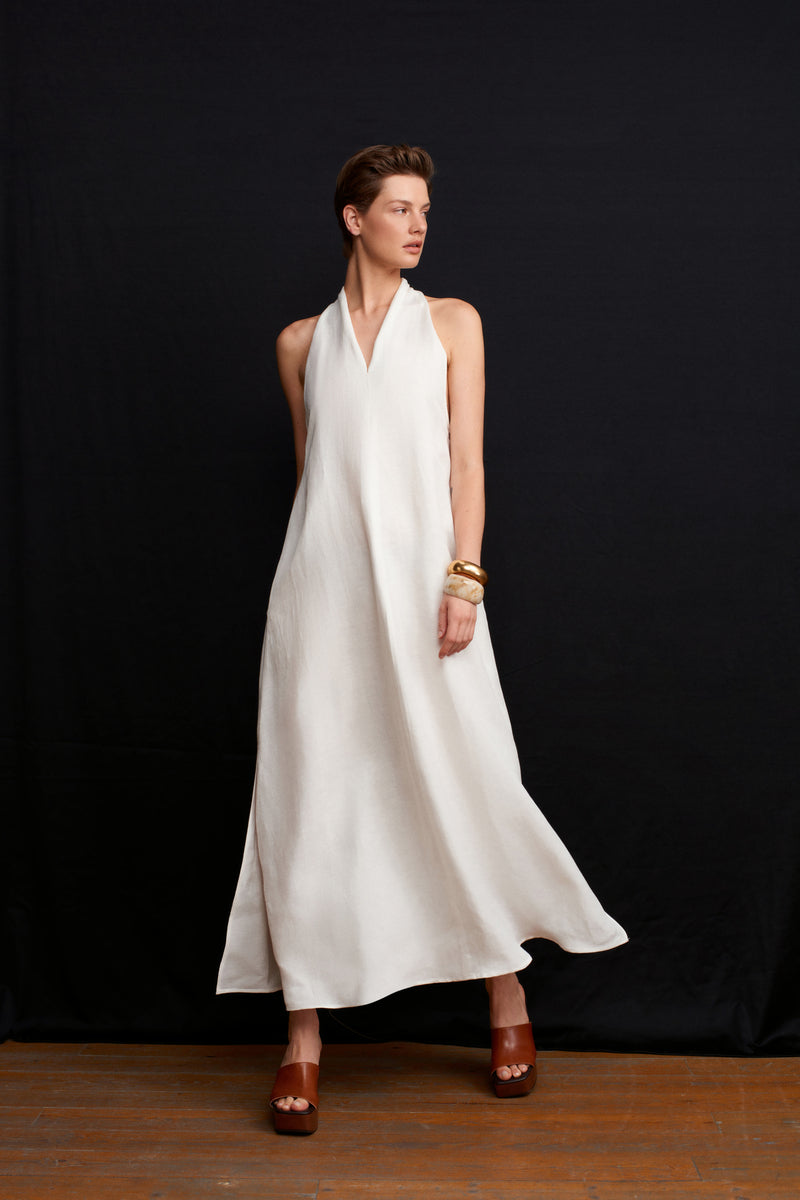 White Acaria Studio La Plage maxi dress displayed on a model, featuring a flowy silhouette and elegant design.