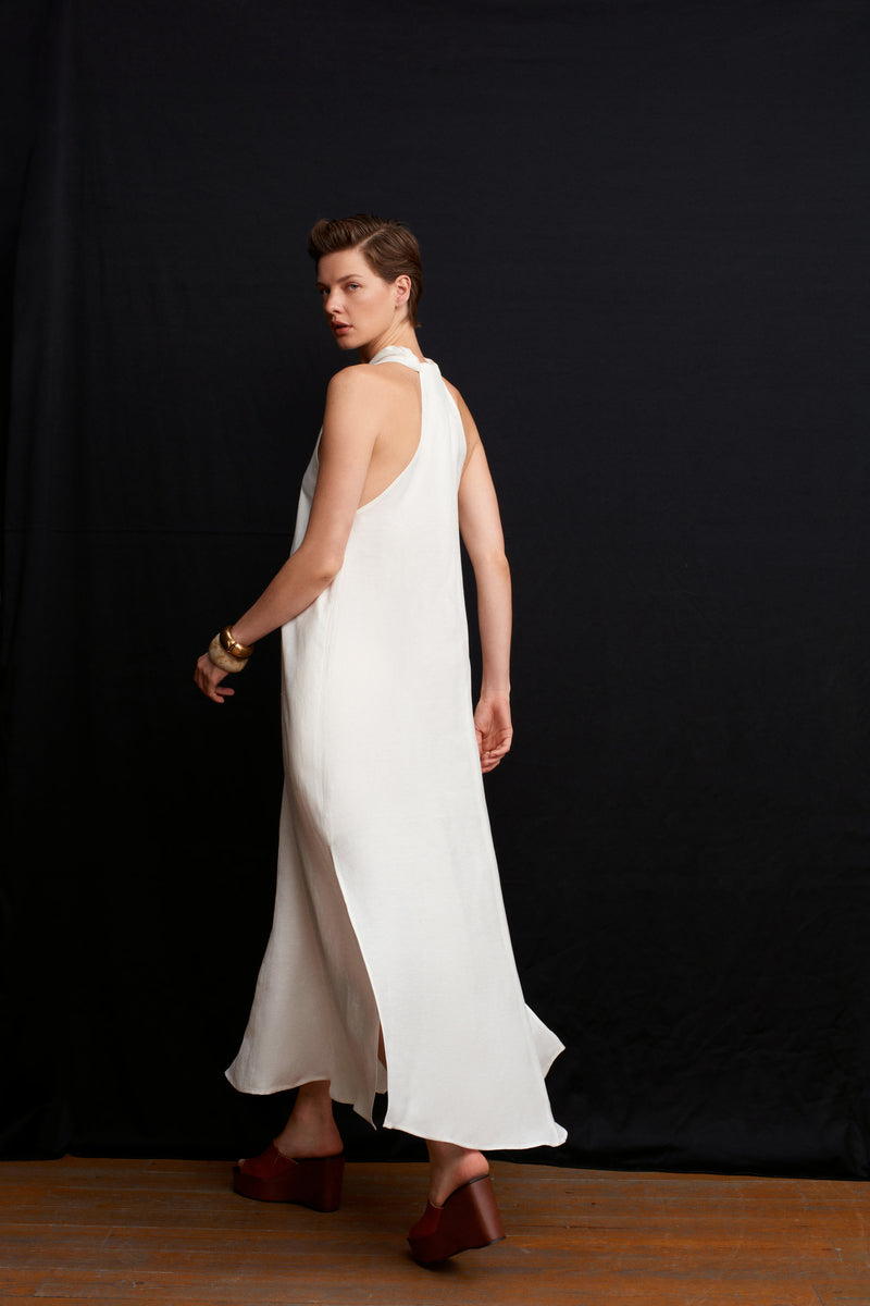 White Acaria Studio La Plage maxi dress displayed on a hanger, showcasing its flowy fabric and elegant summer style.