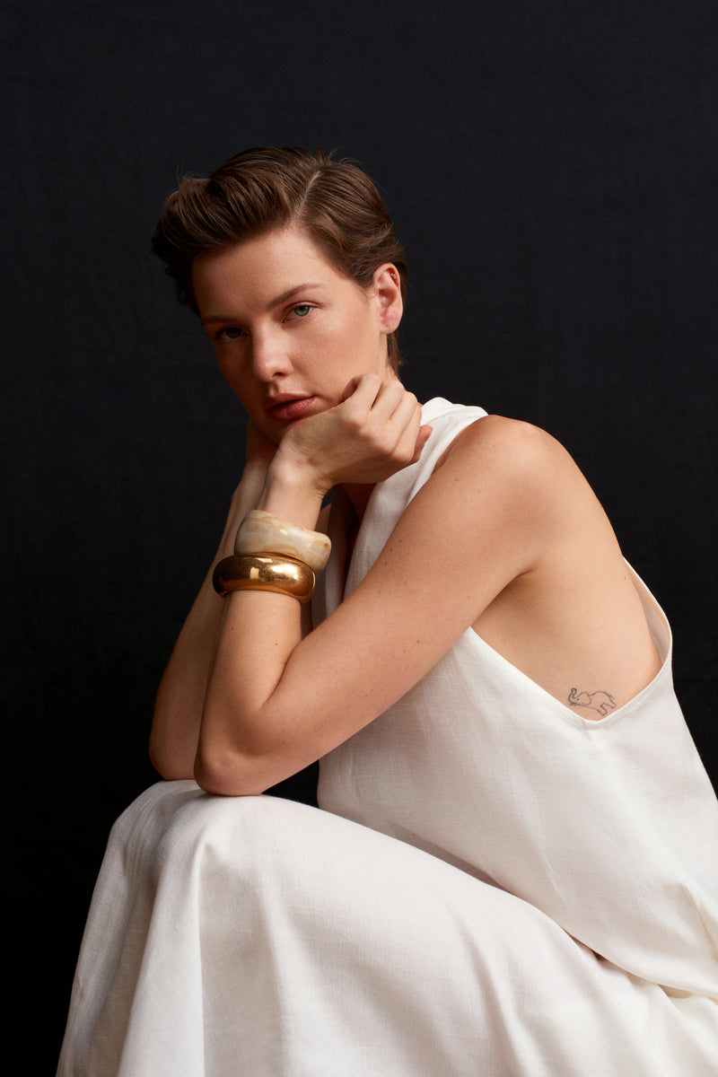 White Acaria Studio La Plage maxi dress displayed on a hanger, featuring a flowing fabric and stylish design.