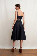 Black Wissy top by Acaria Studio, featuring a stylish design, displayed on a hanger with a plain background.