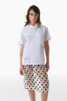 White polo shirt by Gvasalia featuring crystal bow ties and silver accents, showcasing a stylish and elegant design.