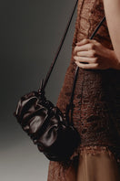 Vikele Studio Rosie shoulder bag in burgundy leather with adjustable strap and minimalist design on a neutral background.