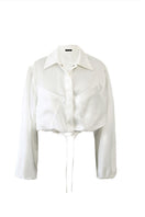 White Kris Marán silky bomber jacket with a smooth fabric finish, stylishly displayed on a hanger.
