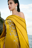 Elegant curved draped off-shoulder gown with long sleeve cape by Tracy Studio, featuring flowing fabric and sophisticated design.