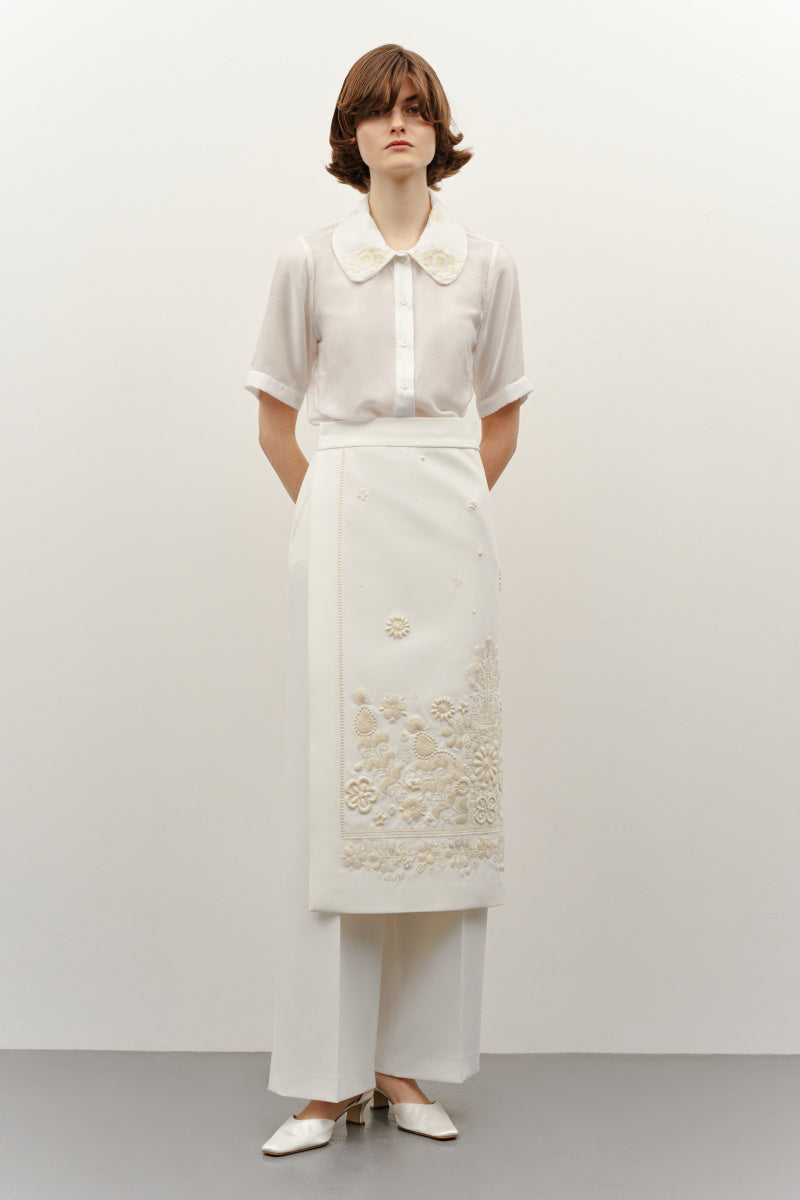 Deligan milk silk shirt with ornamental design, featuring a stylish and smooth fabric, displayed on a hanger.