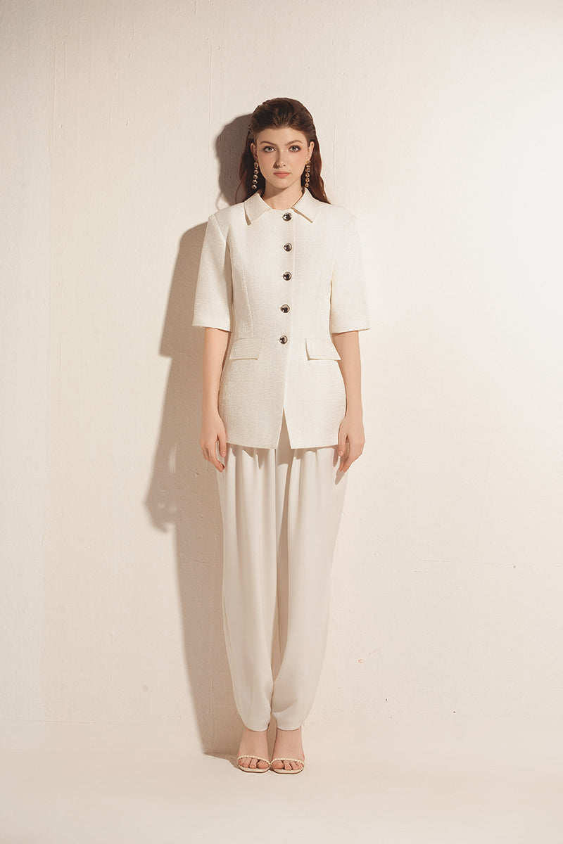 White tapered leg trousers by Valenciani, featuring a sleek fit and clean design, shown on a model.