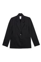 Dāl the Label cotton twill blazer in a tailored fit, featuring a classic collar and button closure, displayed on a hanger.