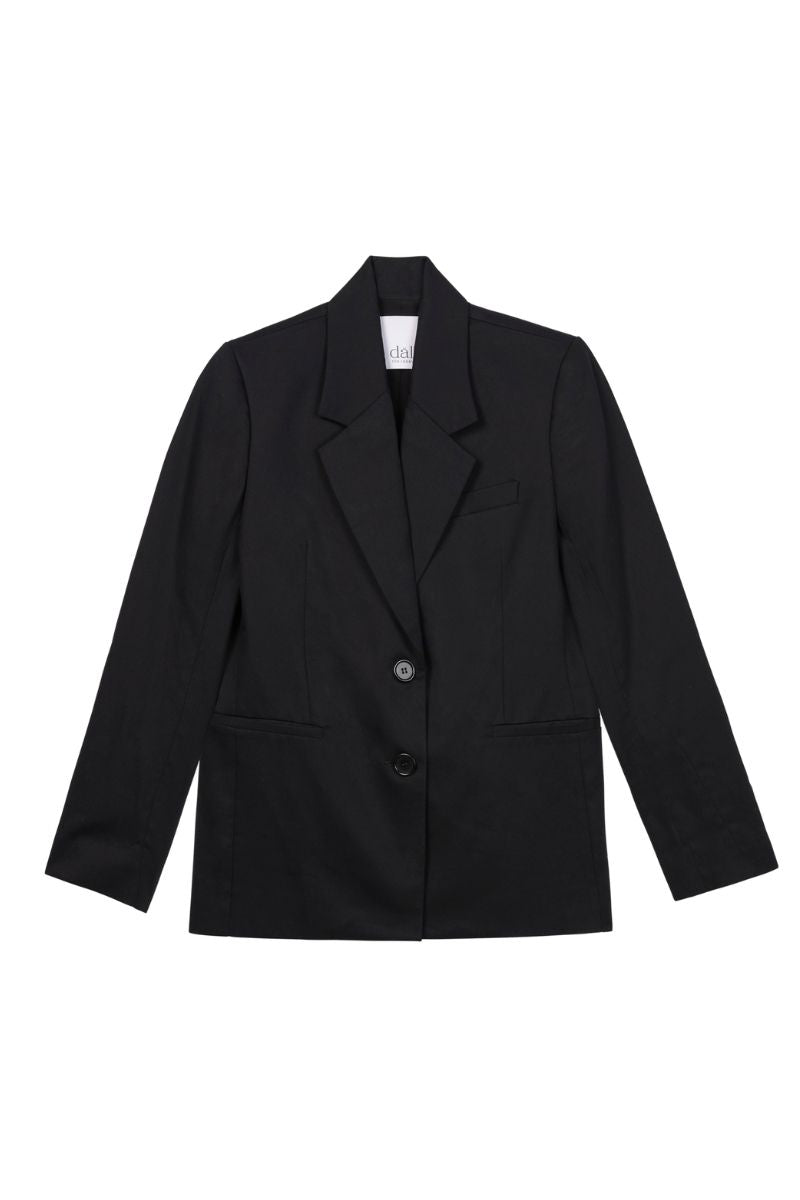 Dāl the Label cotton twill blazer in a tailored fit, featuring a classic collar and button closure, displayed on a hanger.