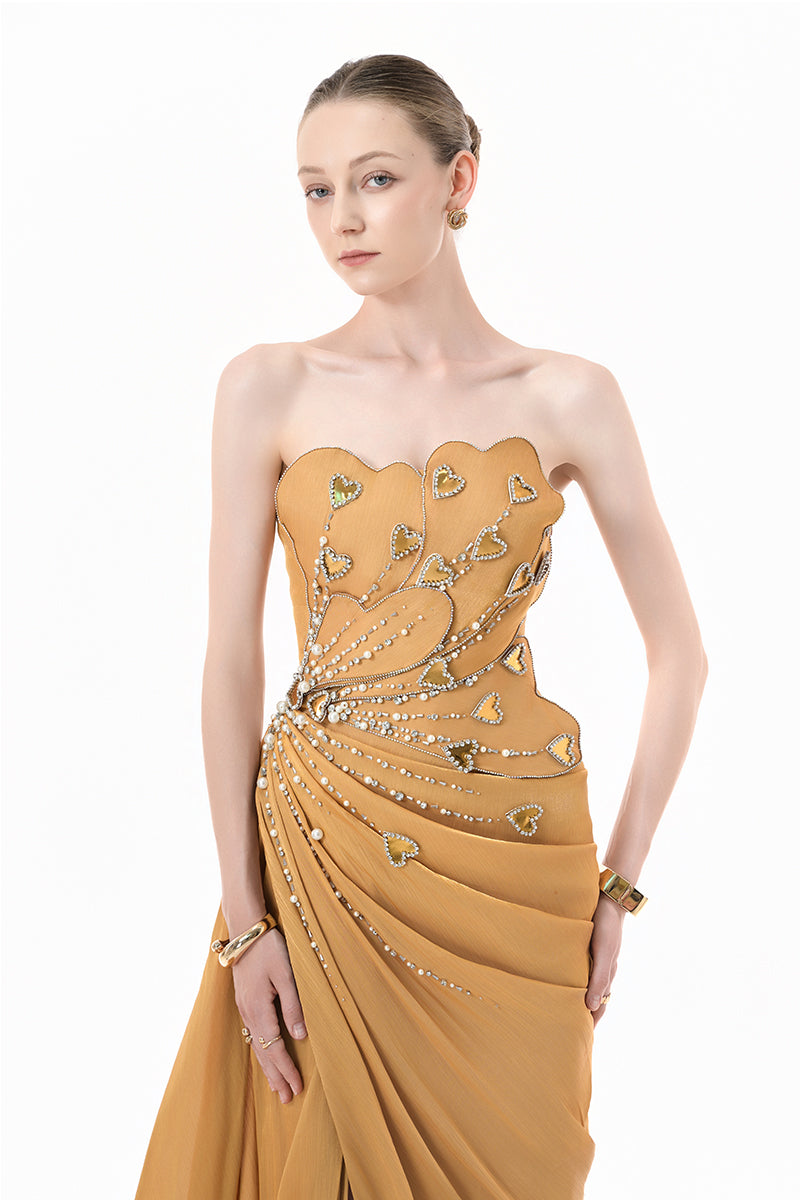 Elegant chartreuse gold gown with heart embellishments and draped design by Happy Clothing, featuring flowing fabric and intricate detailing.