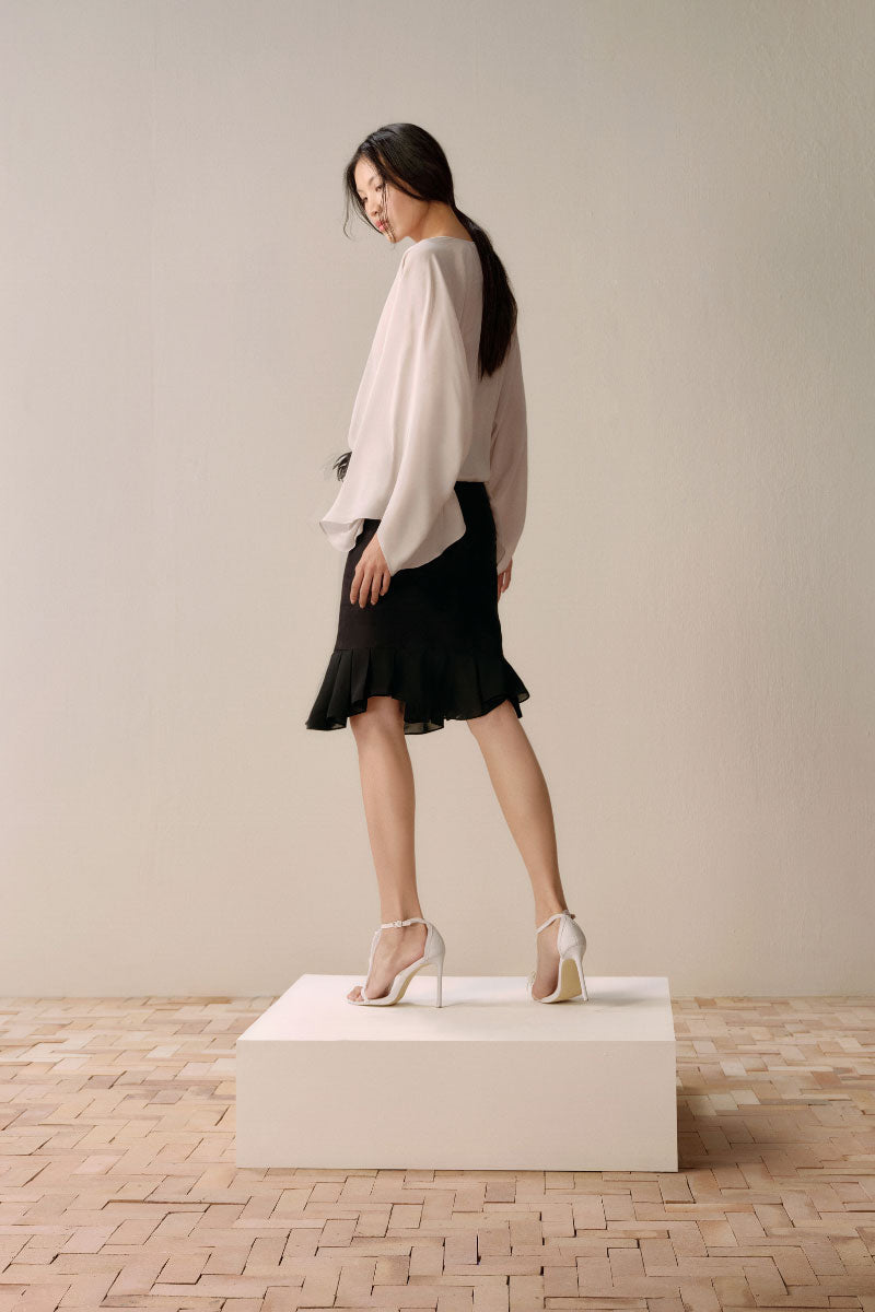 Black Leicia trumpet midi skirt featuring a fitted waist and flared hem, styled in a sleek, elegant silhouette.