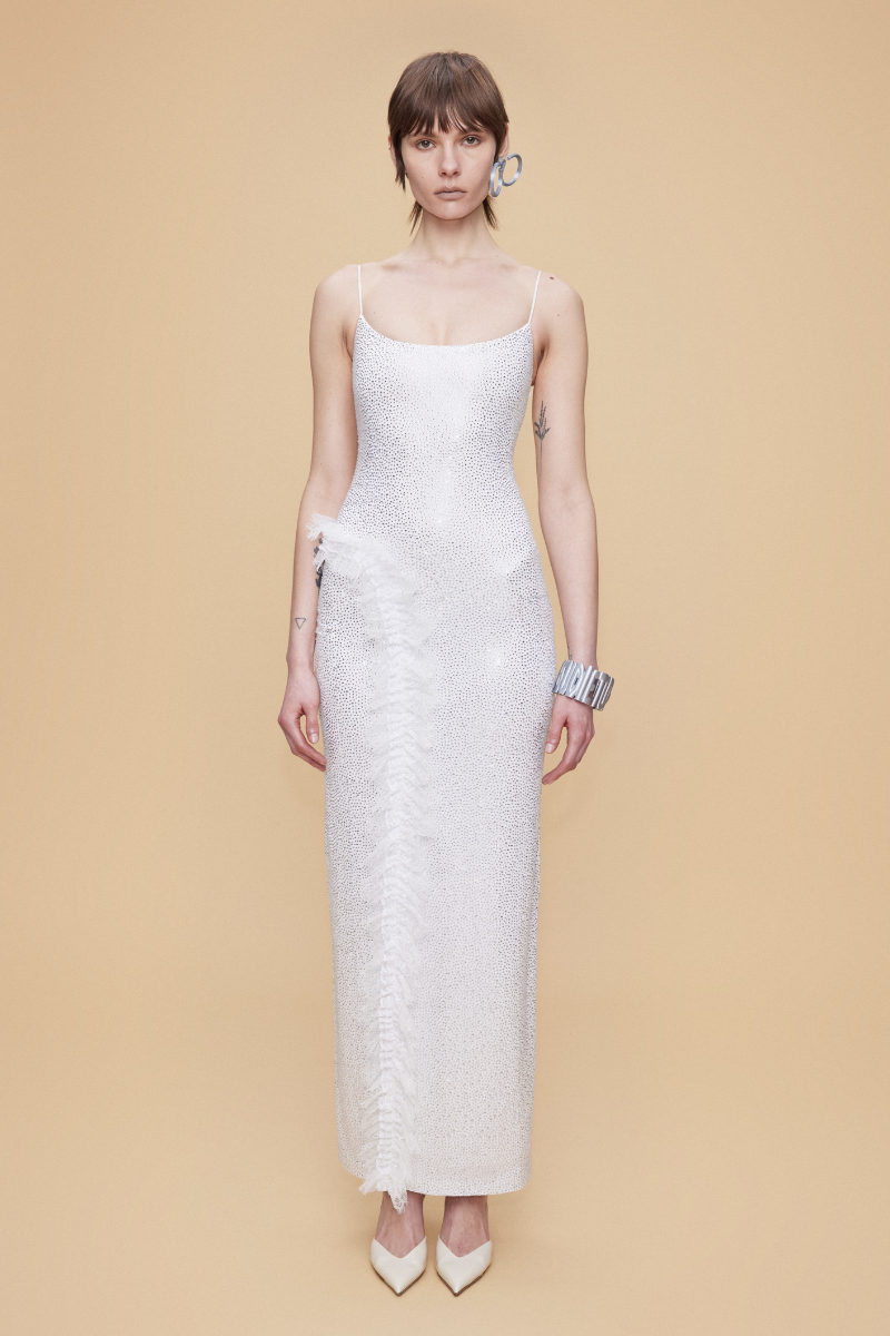 White fully rhinestone-embellished maxi dress with lace ruffle detail by Sudi Etuz, showcasing elegant design and intricate embellishments.