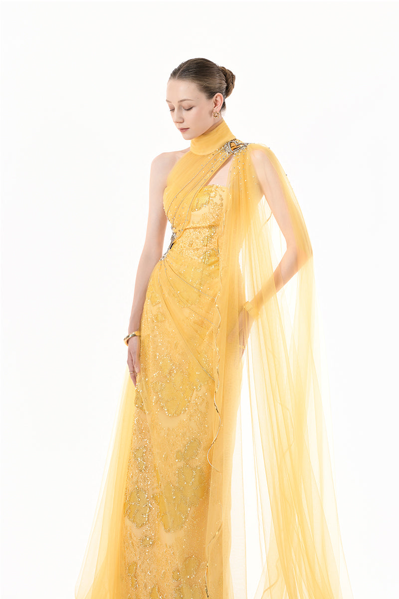 Golden yellow embellished tulle cape gown by Happy Clothing, featuring intricate embroidery and flowing fabric for elegant occasions.