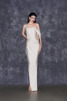 Cream asymmetrical sleeved floor-length gown by CEM featuring elegant draping and flowing fabric on a model.