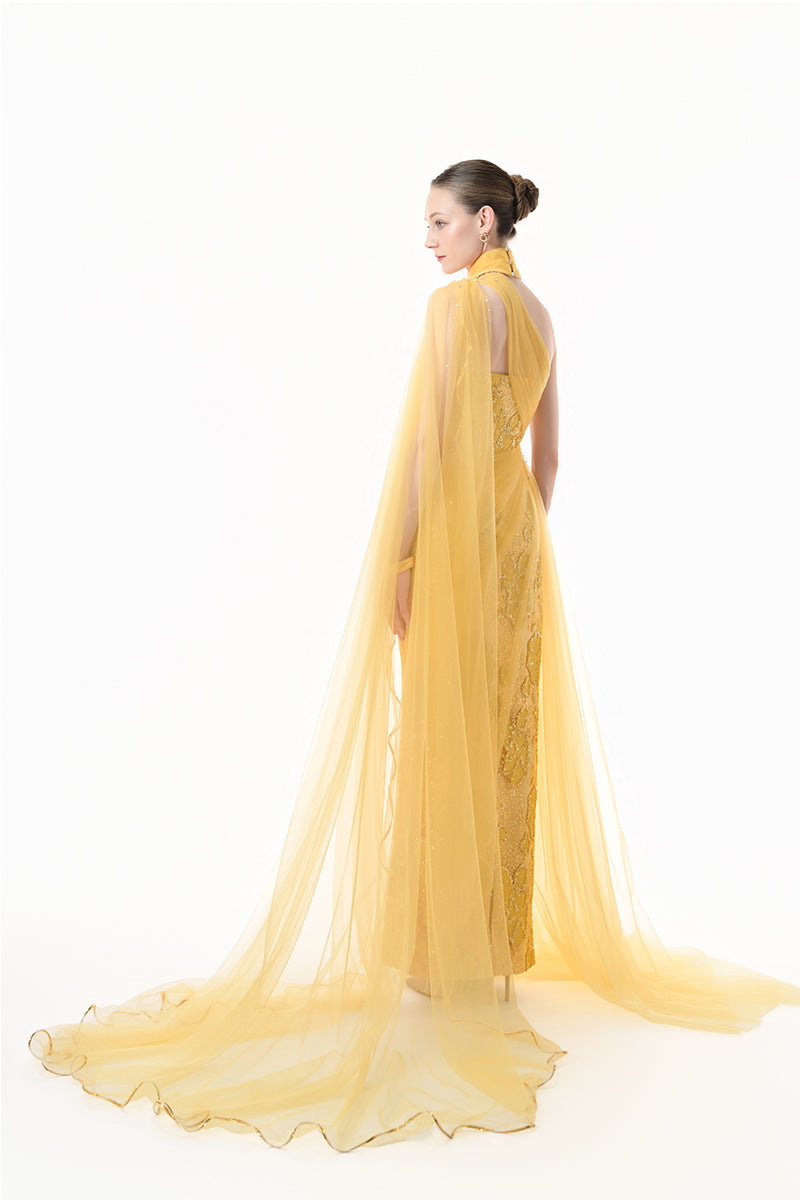 Golden yellow embellished tulle cape gown by Happy Clothing, featuring intricate embroidery and flowing fabric, perfect for elegant occasions.