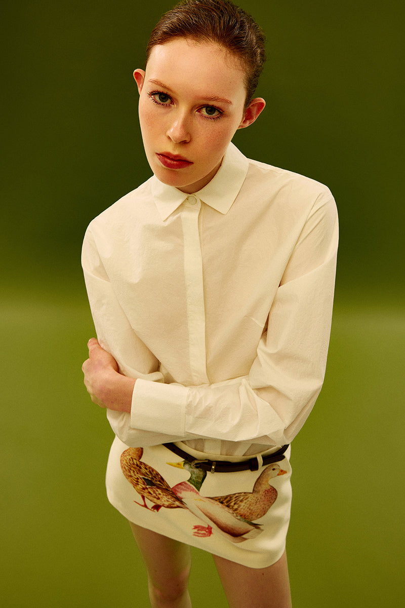 Chictopia ivory poplin shirt with long sleeves and classic collar, displayed on a hanger in a well-lit setting.