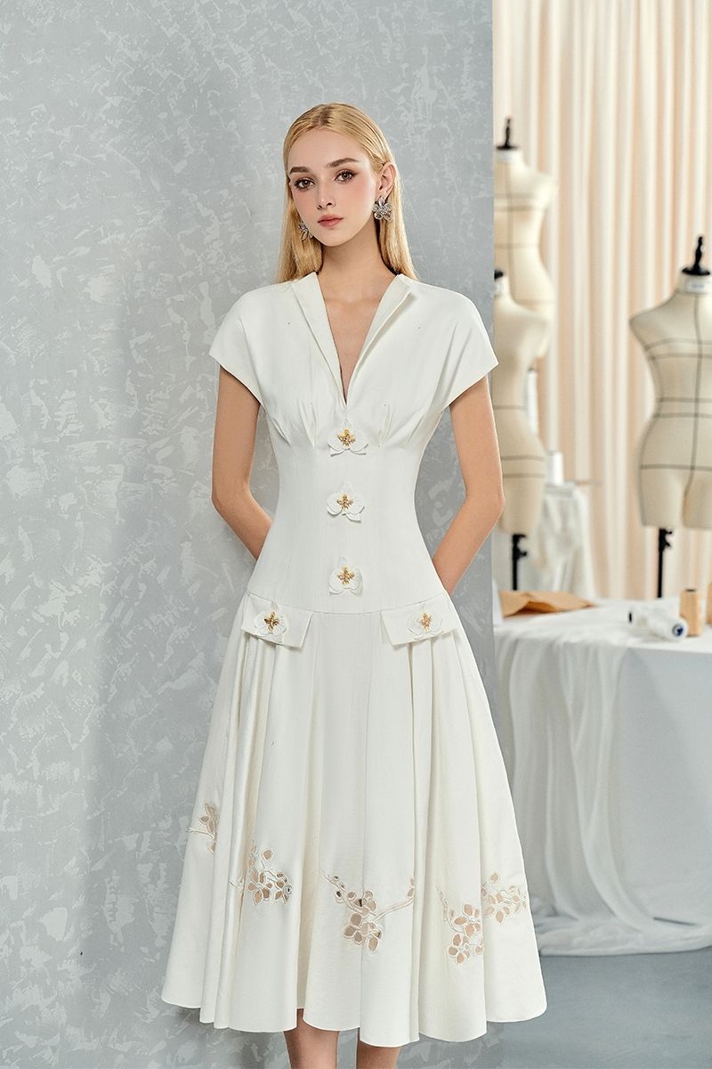 White sleeveless shirt and orchid-flowered midi dress by Do Long, styled together in a fashion photo.
