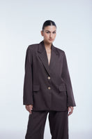 Relaxed single-breasted blazer by Dāl the Label, shown in a natural fit with lapels and tailored style.