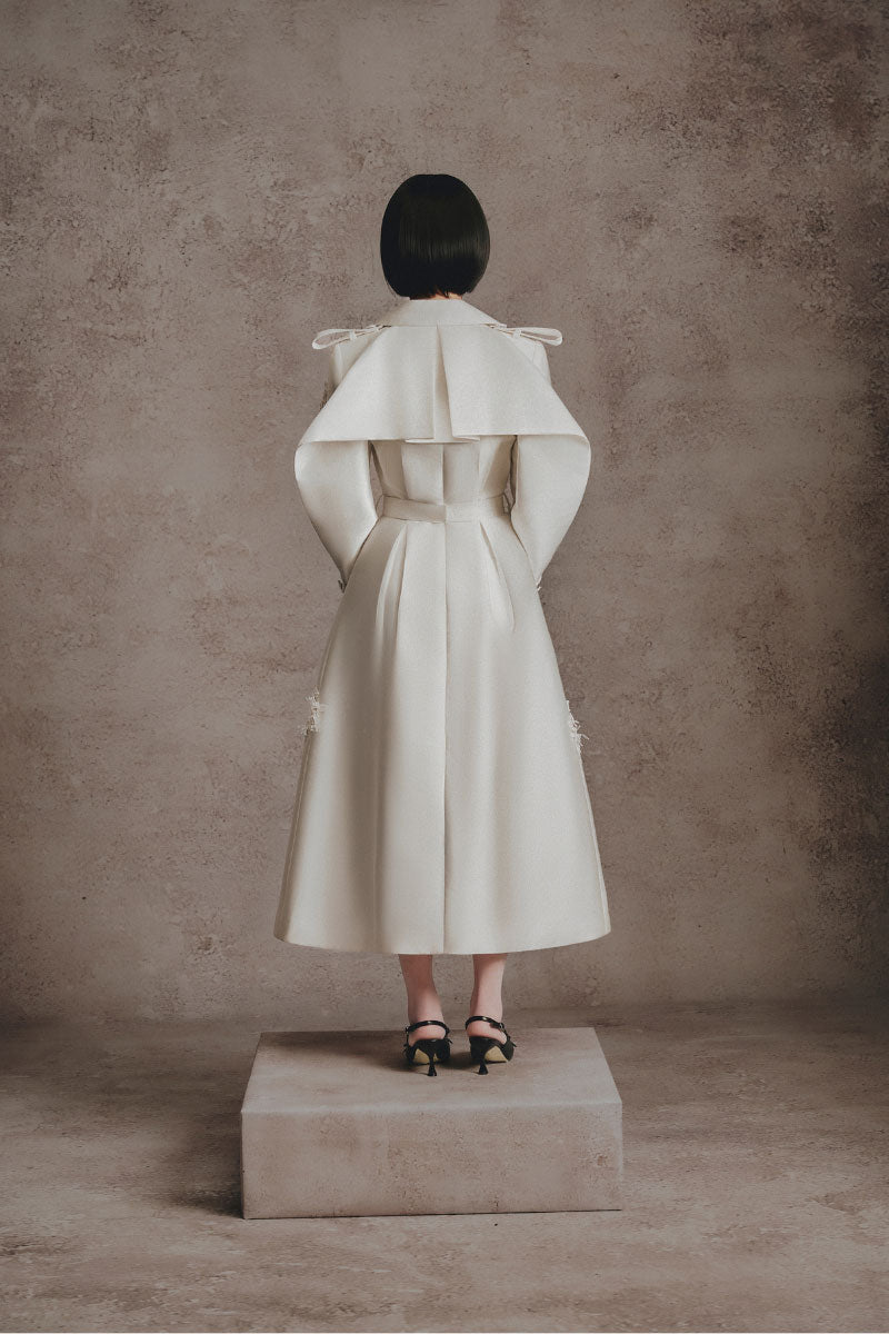 Ivory embroidered trench coat by White Plan featuring detailed embroidery, classic collar, and button closure.