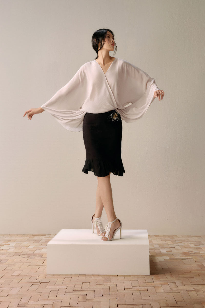 Black Leicia trumpet midi skirt displayed on a hanger, showcasing its fitted waist and flared silhouette.