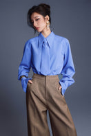 Blue New Thera Shirt by Keira Tong, featuring a casual fit and soft fabric, displayed on a hanger against a neutral background.
