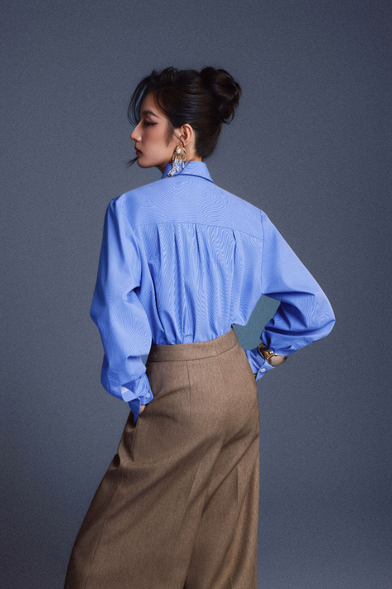 Blue New Thera shirt by Keira Tong, featuring a casual fit with button-down front and collar, displayed on a hanger.