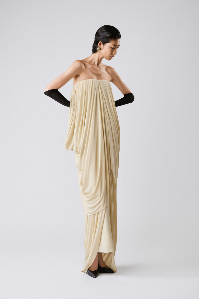 Elegant butter-colored gown by TONYY, featuring flowing fabric and intricate design, perfect for formal occasions.