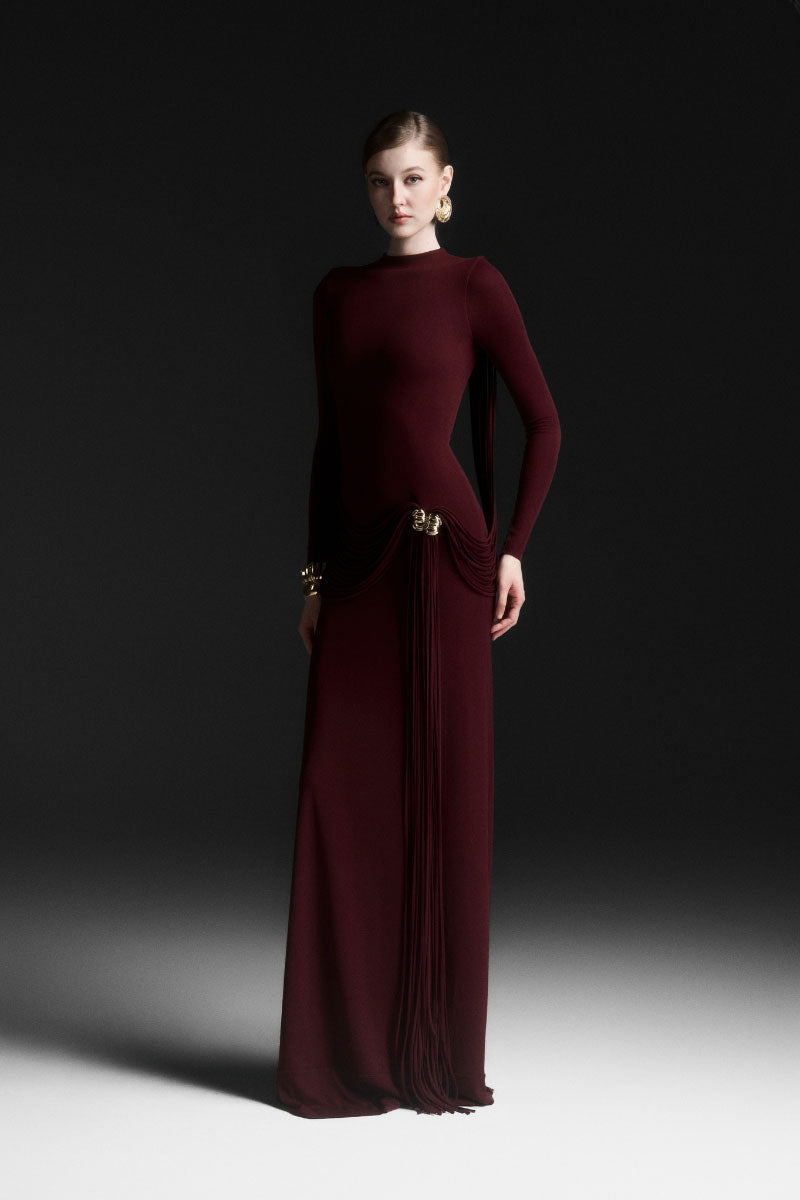 Red Maison Des Copains corvina draped floor length maxi dress shown on a hanger with flowing fabric and elegant design.