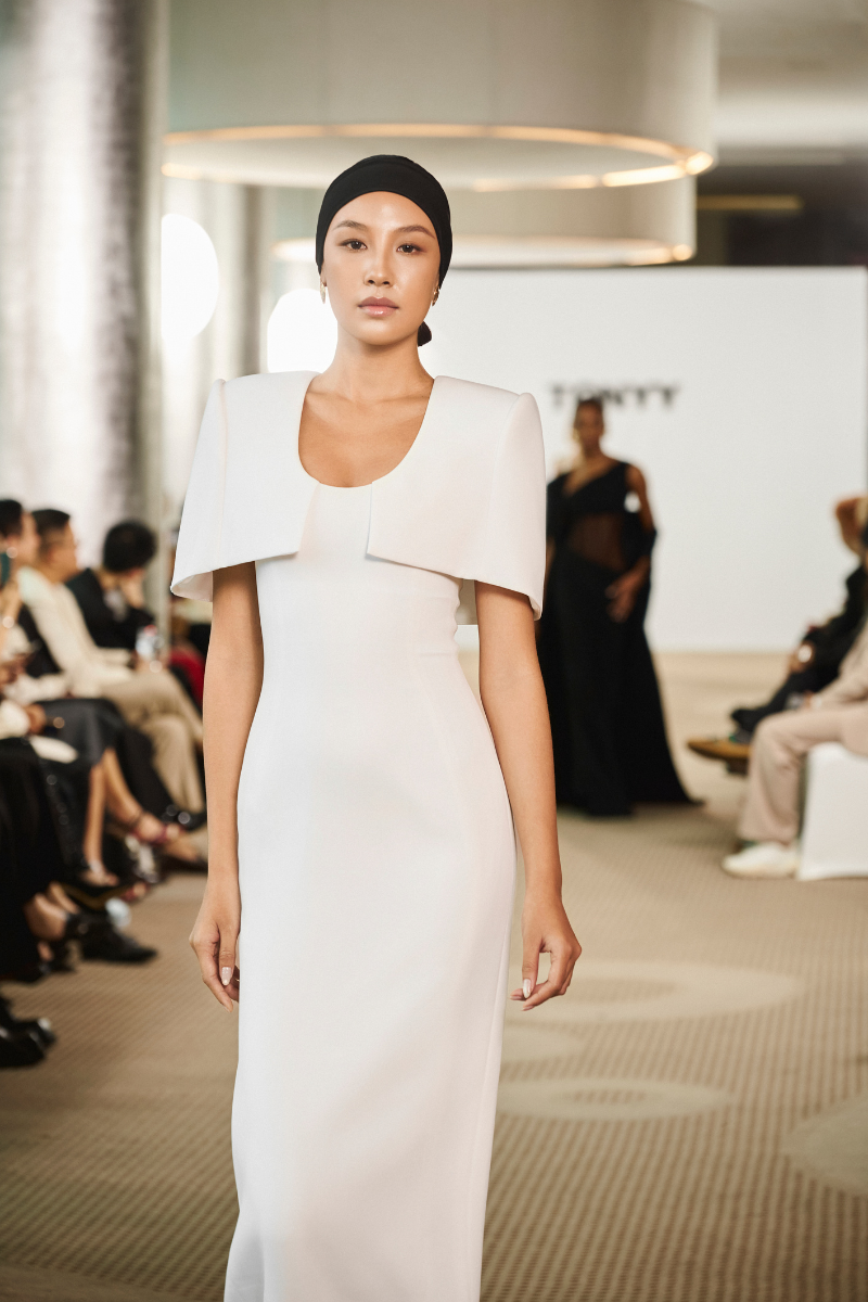Elegant SILKEN WHISPER gown by TONYY featuring flowing fabric and intricate detailing, displayed on a mannequin.
