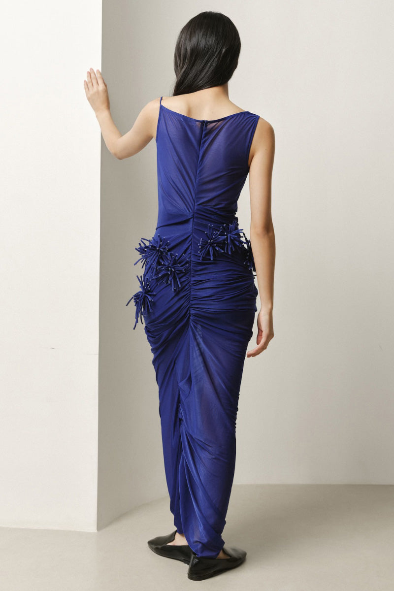 Lecia draped pom-pom sheer maxi dress with flowing fabric and decorative pom-pom accents, perfect for elegant summer occasions.