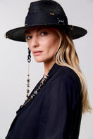 Black fedora hat by LE SH KA with shell embellishments and 24K gold-plated accessories, featuring a stylish wide brim and decorative details.