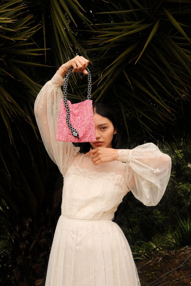 Small pink Serpent shoulder bag by SAC DE SOUL with black and white accents, featuring a textured snake print design.