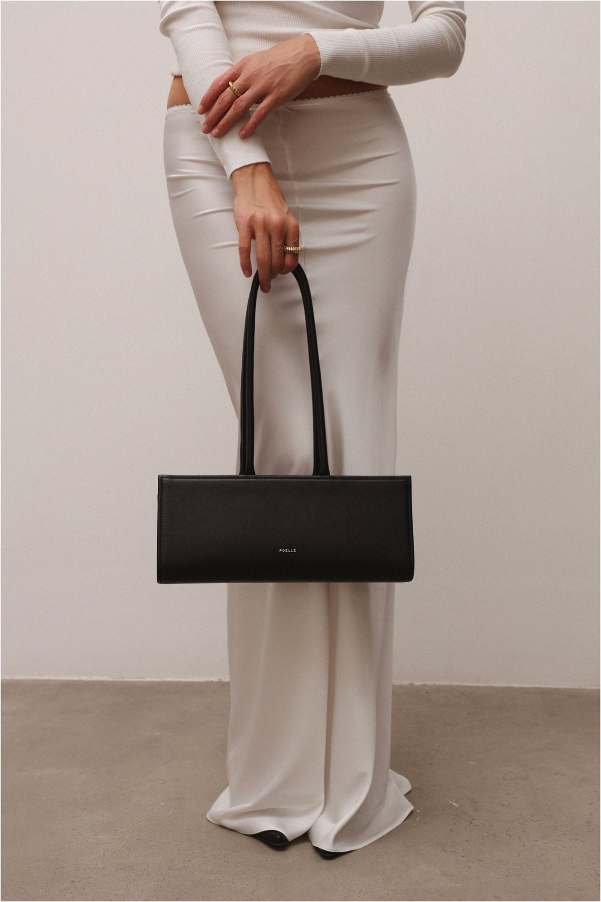 Black Poelle Cecilie top handle bag with sleek design and structured silhouette, featuring elegant handles and minimalist style.