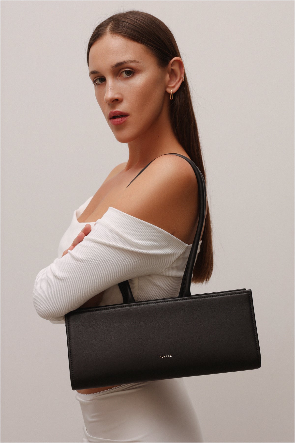 Poelle Cecilie black top handle bag with sleek design, featuring a structured shape and elegant carry handle.