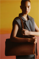 Medium dark brown leather shoulder tote bag from POELLE's Carolyn collection, featuring a spacious design and sturdy handles.