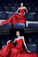 Red draped corset gown by CEM, featuring elegant fabric and fitted design, perfect for formal occasions.