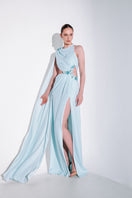 Blue embellished cape gown by Monika Dimova featuring intricate detailing and flowing fabric, perfect for formal occasions.