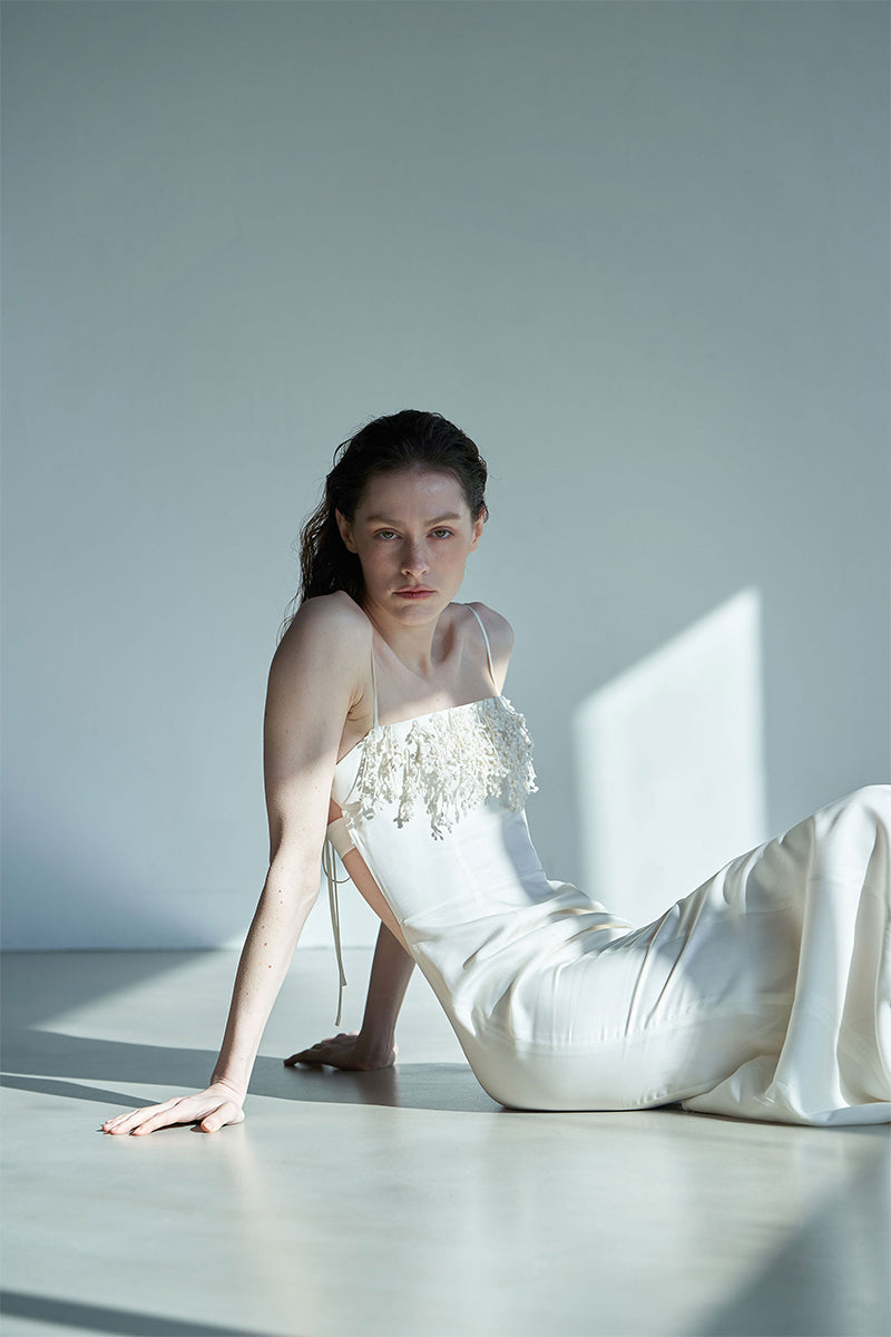JINSUN botanical embellished ivory cupro gown displayed on a hanger with floral embroidery and flowing fabric.