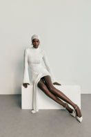 Khanum's KALESY white mini dress displayed on a hanger, featuring a fitted silhouette and sleeveless design for a chic look.