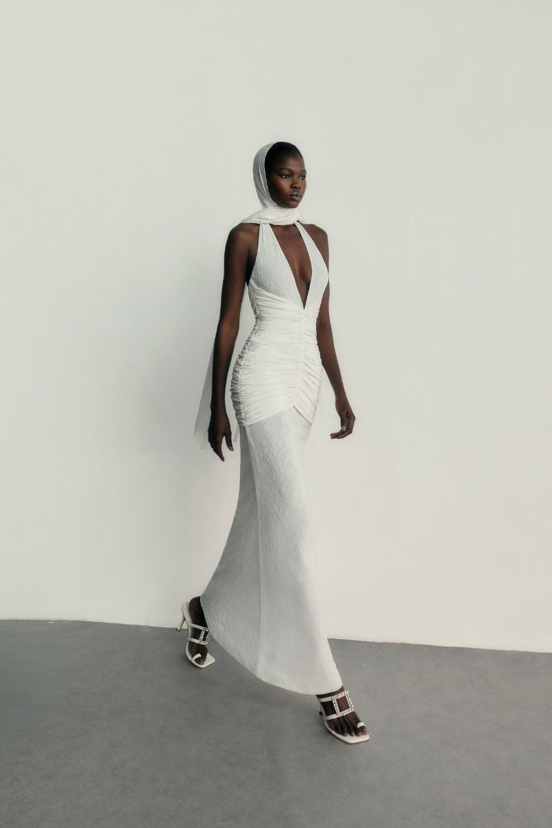 Khanum's Kaylin white maxi dress with flowing fabric and elegant design, displayed hanging on a wooden hanger.